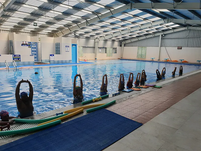 Swimmers training in an indoor pool hall under a PEB roof