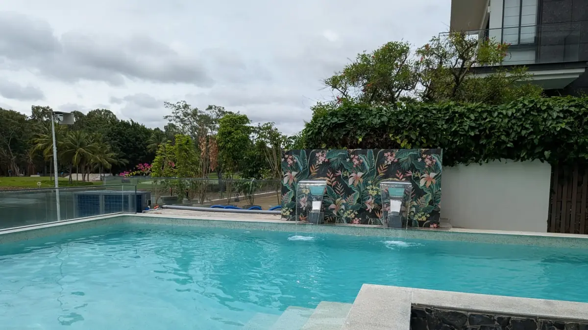 Outdoor pool with a printed tile feature wall and water jets at Dinesh Residence